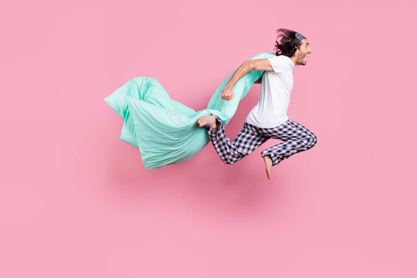 Full size profile side photo of young crazy smiling man look copyspace jumping with blanket isolated on pink color background - Fotografie, Obrázek