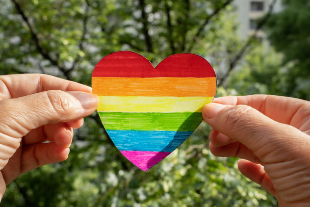 ručně malované srdce v barvách vlajky Igbtq + v rukou ženy. koncept tolerance, rozmanitosti, usmíření mezi lidmi - Fotografie, Obrázek