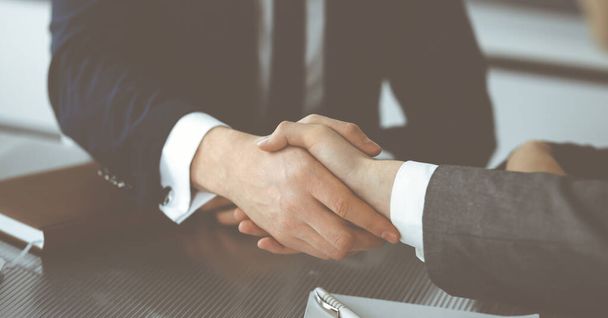 Unknown businessman shaking hands with his colleague or partner above the glass desk in modern office, close-up. Business people group at meeting - Φωτογραφία, εικόνα