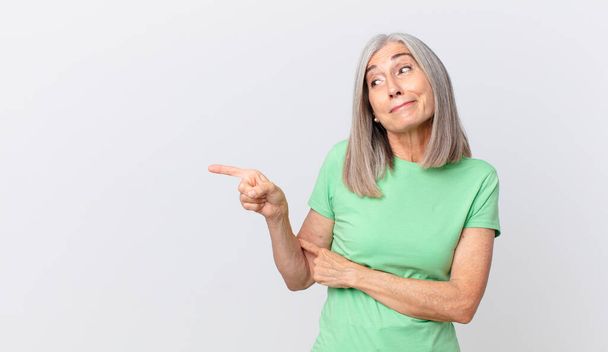 middle age white hair woman shrugging, feeling confused and uncertain and pointing to the side - Photo, image
