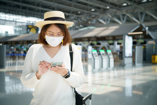 新しい通常の観光客の顔のマスクを着て空港で旅行しています。社会的距離医療システム、安全な滞在と旅行バブルの概念. - 写真・画像