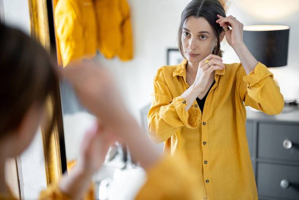 La mujer se mira en el espejo, preparándose para salir - Foto, imagen