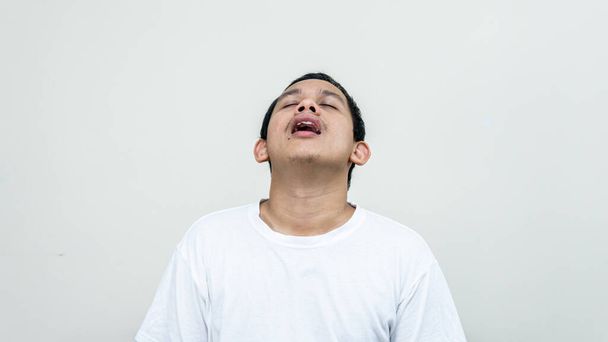 Un ritratto di un uomo malese asiatico stanco con gli occhi bianchi di chiusura t-shirt sospirato stanco e infastidito su sfondi bianchi isolati. Brutto umore con lavoro pesante. - Foto, immagini