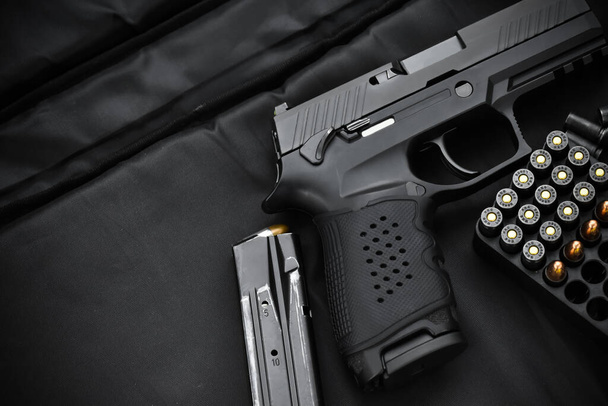 Automatic 9mm black pistol and bullet on black background. Soft and selective focus on pistol's grip. - Photo, Image