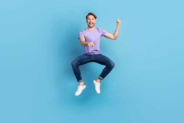 Full length body photo of young man jumping high imagine riding horse isolated on pastel blue color background - Foto, afbeelding