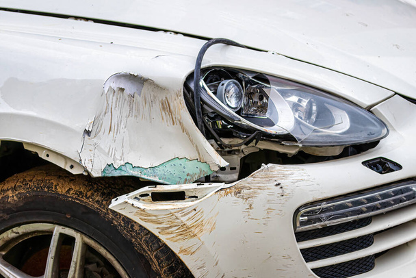 Een kapotte auto na een ongeluk. Beschadigde vleugel en koplamp van een auto, deuken en krassen op een carrosserie.  - Foto, afbeelding