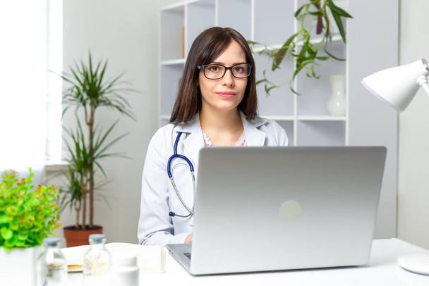 thérapeute féminine assise au bureau avec ordinateur portable et bocaux - Photo, image