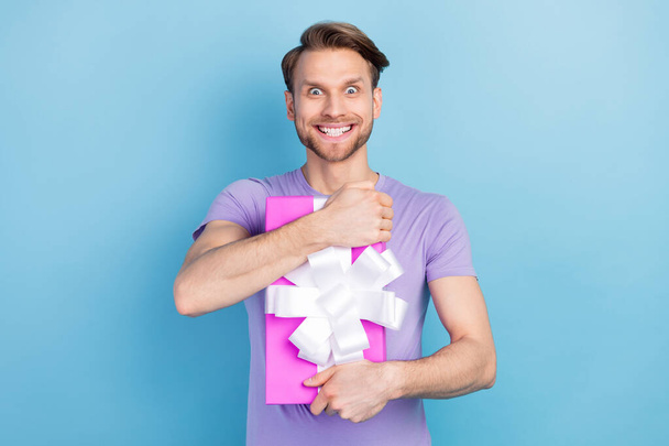 Photo portrait of crazy man embracing present box on party staring isolated on pastel blue color background - Foto, afbeelding