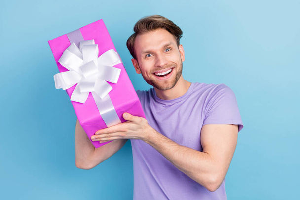 Photo of astonished positive young person hands hold giftbox near ear isolated on blue color background - Foto, Imagem