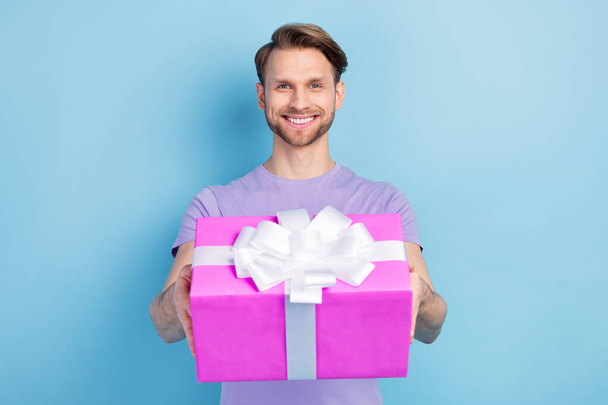 Photo portrait of smiling man giving present box on party isolated on pastel blue color background - Valokuva, kuva