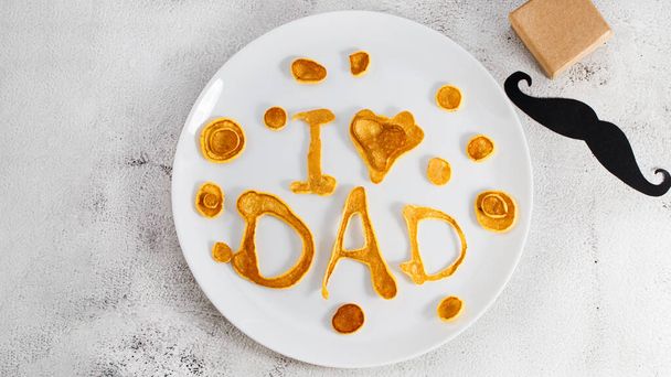 Celebrating Father's Day. Breakfast: pancakes in form of congratulations - I love dad , and coffee mug and . copy space. - Fotó, kép