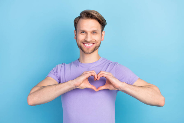 Photo portrait of guy showing heart with fingers on date smiling isolated on pastel blue color background - Фото, зображення