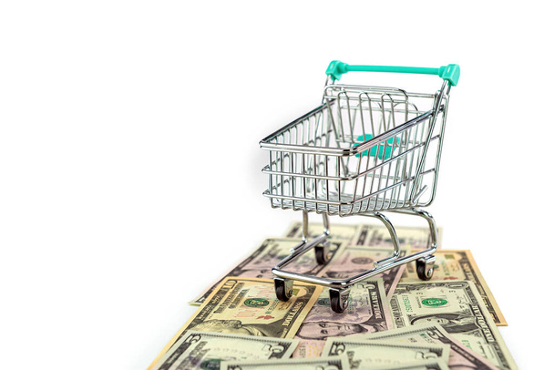 shopping cart on US dollars banknotes way isolated on white background, selective focus - Foto, afbeelding