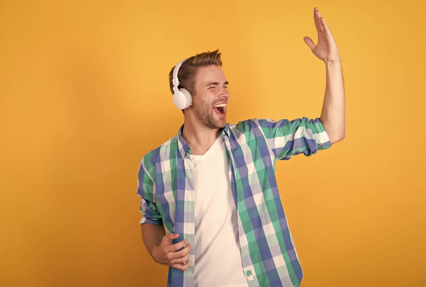 Happy guy enjoy music in headphones yellow background, singing - Foto, Bild