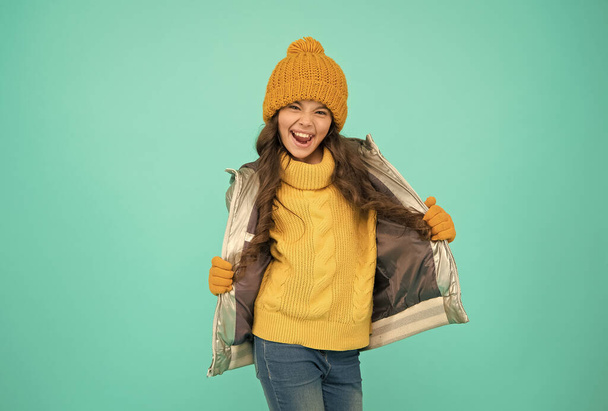 χαμογελαστό έφηβο κορίτσι με παραγεμισμένο ή puffer σακάκι έτοιμο να περάσει τις χειμερινές διακοπές και διακοπές στην άνεση και ζεστασιά, ανέμελη και αστεία - Φωτογραφία, εικόνα