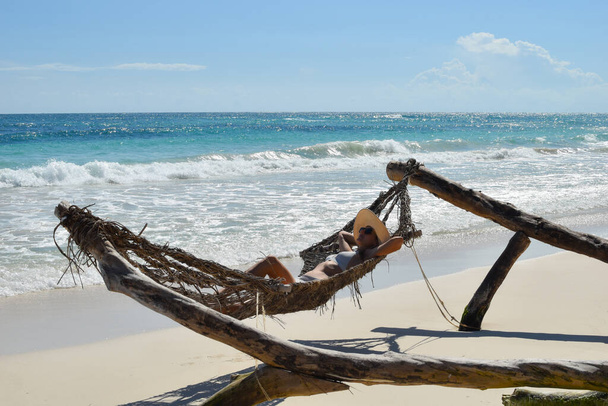 A woman in a swimsuit sunbathes in a hammock on a tropical beach. - Photo, image