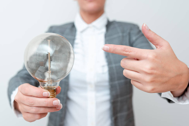 Дама вказує на лампу, що проводиться в руці в офіційному вбранні представляючи нові ідеї для проекту, бізнес-леді Керівництво Лампа виставляє нещодавно випущені технології, Lightbulb Veiwing свіжа ідея
 - Фото, зображення