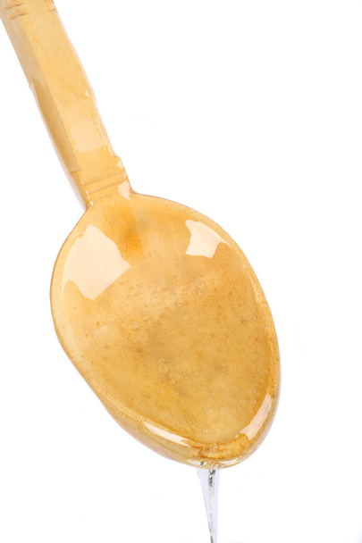 Miel goteando por la cuchara de madera
 - Foto, Imagen