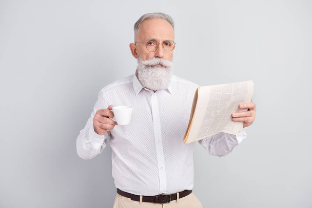 Photo of serious old calm smart imposing man hold cup of tea newspaper isolated on grey color background - Foto, Imagen