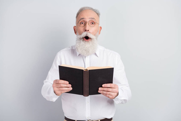 Photo of handsome impressed grey hair old man boss hold book wear spectacles shirt isolated on grey background - Foto, imagen