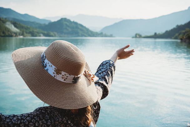 kobieta z kapeluszem podziwiając widok na jezioro - Zdjęcie, obraz