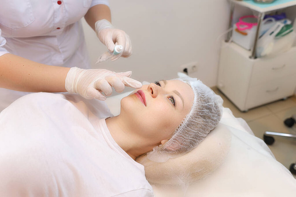 Il cosmetologo prepara le labbra del cliente per la procedura di aumento - Foto, immagini