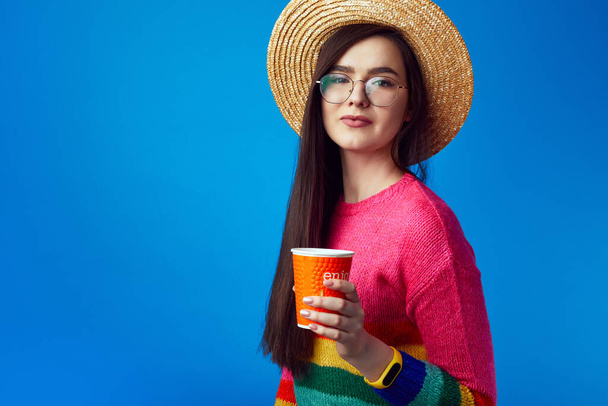 Giovane ragazza con gli occhiali in possesso di un caffè da asporto, ha espressione gioiosa - Foto, immagini