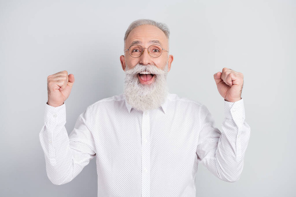 Photo of amazed cheerful old man raise fists winner celebrate good mood isolated on grey color background - Foto, immagini