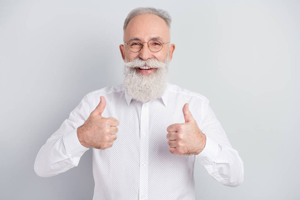 Foto de feliz encantador hombre viejo positivo usar gafas muestran pulgar-up aislado en fondo de color gris - Foto, imagen