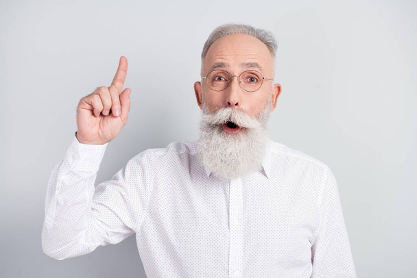 Portrait of handsome impressed grey hair old man point up wear spectacles white shirt isolated on grey color background - Фото, изображение
