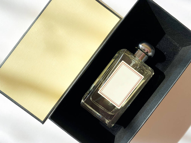 Egy üveg parfüm egy sárga dobozból, fehér, elszigetelt háttérrel. - Fotó, kép