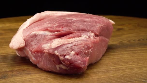 Un pezzo di carne di maiale fresca cruda su una superficie di legno - Filmati, video