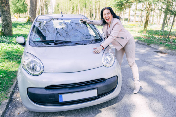 Mutlu kadın sürücü arabanın anahtarlarını gösteriyor ve açık araba kapısının yanında duruyor. Satın almaktan memnun. - Fotoğraf, Görsel