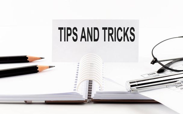 Text Tips and tricks on the paper card,pen, pencils, glasses,financial documentation on table - business concept - Photo, Image