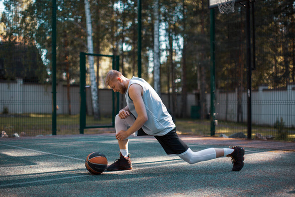 Professional sportive male american basketball player warming up on court before play outdoors in summer - Fotoğraf, Görsel