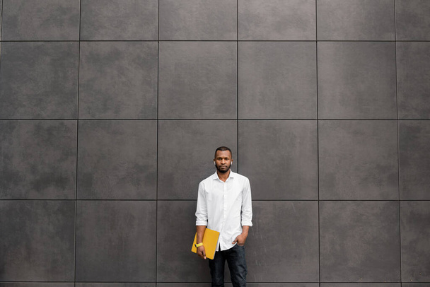 young african american man  standing near wall with laptop  - Фото, зображення