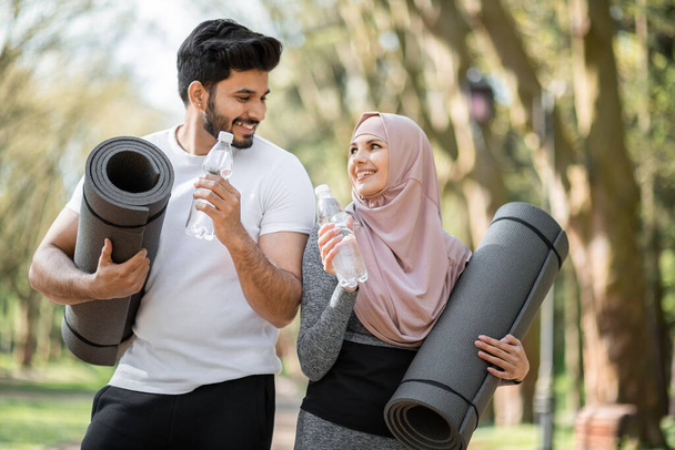 Arabian family with water bottle and yoga mat at park - Photo, image