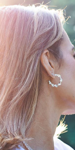 Γυναίκα που φοράει σκουλαρίκια. Σκουλαρίκια στο αυτί νεαρής γυναίκας, γυναικεία αξεσουάρ, χρυσά σκουλαρίκια - Φωτογραφία, εικόνα