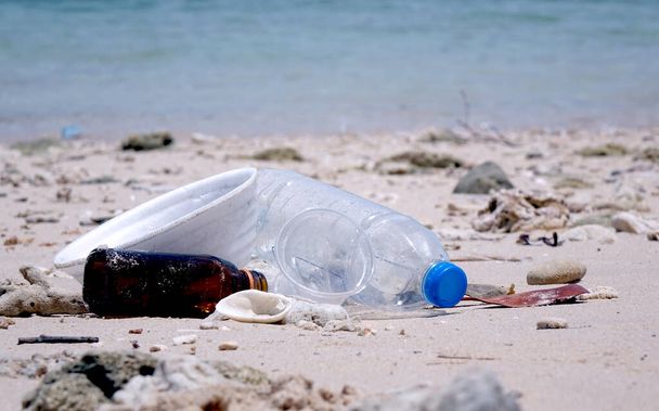Contaminación: Contaminación de las playas marinas. Tazón de fideos instantáneo de espuma de poliestireno, taza de plástico, vidrio y botellas de plástico en la playa. Enfoque selectivo y espacio de copia - Foto, Imagen