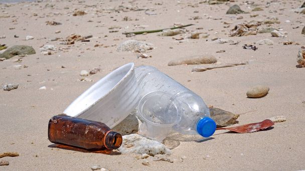Contaminación: Contaminación de las playas marinas. Tazón de fideos instantáneo de espuma de poliestireno, taza de plástico, vidrio y botellas de plástico en la playa. Enfoque selectivo y espacio de copia - Foto, Imagen