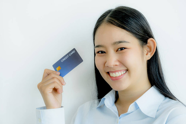 Portret uroczej, młodej Azjatki, pięknej kobiety z długimi włosami, trzymającej niebieską kartę kredytową, błyszczące oczy przed kamerą. Gotowy do zapłaty zakupy według produktów dyskontowanych. - Zdjęcie, obraz