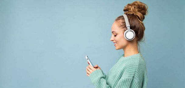 Panoramiczny boczny profil zdjęcie piękne radosne uśmiecha się młoda kobieta osoba w stylowy strój casual odizolowany na kolorowe tło ściany noszenia białego bluetooth bezprzewodowych słuchawek i - Zdjęcie, obraz