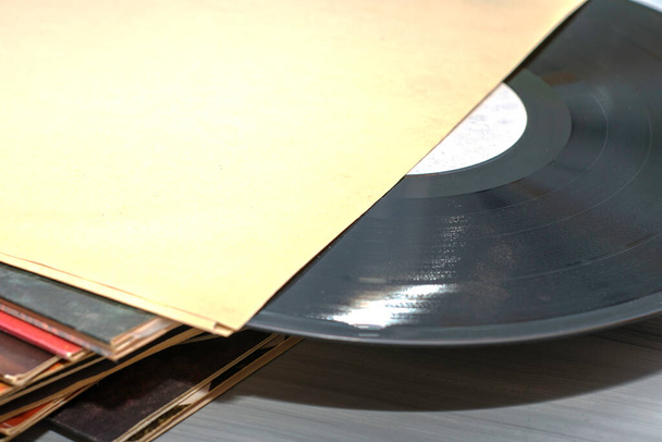 Una pila de discos de vinilo viejos cierran uno de los discos está medio fuera del sobre. Foto de alta calidad - Foto, imagen