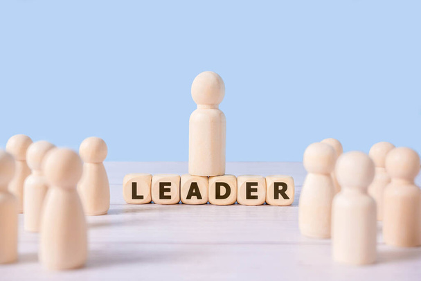 Leader word on wooden blocks and group of wooden figure on blue background.Successful team leader,Businessman people standing out from the crowd.Concept of working is organization with corporation - Foto, Imagem