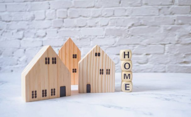 Miniatuur huis en houten blokken met het woord thuis op marmeren tafel.Vastgoed concept.Huur appartement. Eigendom. Verhuur, verhuur van huis. Kopen. Aankoop van woningen - Foto, afbeelding
