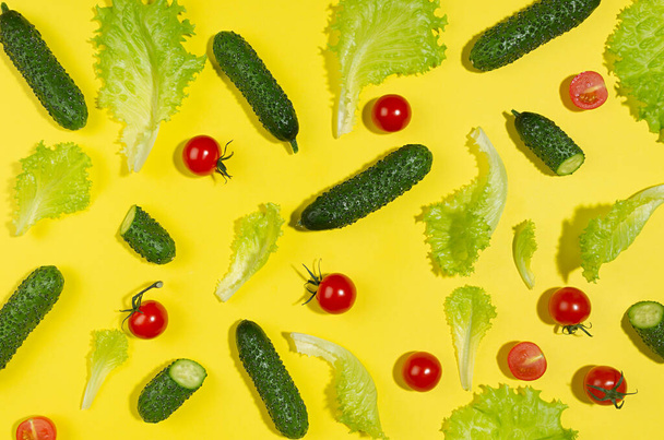 Food color pattern - ripe cherry tomato, green gherkin cucumber, salad leaves with shadow on yellow background, top view. - Foto, immagini