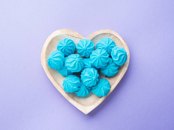 Деревянное блюдо в форме сердца с голубыми сладкими безе - Фото, изображение