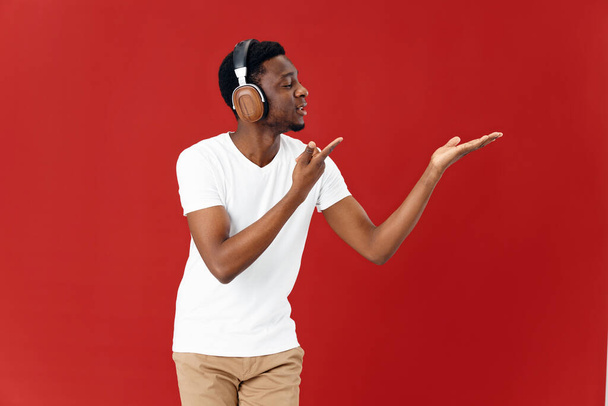 Vidám afrikai külsejű férfi fülhallgatóban. Zene szerető életmód piros háttér - Fotó, kép