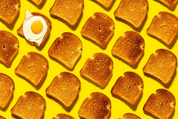 Gebakken brood tot goudbruin, roerei als ontbijt. Knapperige koolhydraten op een felgele achtergrond. Bovenaanzicht. - Foto, afbeelding
