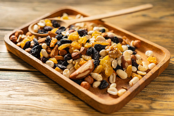 Nut cocktail. Fitness nutrition. Vegetarian snack mix. Wooden table top, wooden bowl. A natural product. - Photo, Image